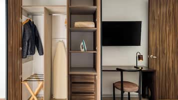 Una habitación moderna con un armario de madera, un escritorio con silla y una percha con ropa.