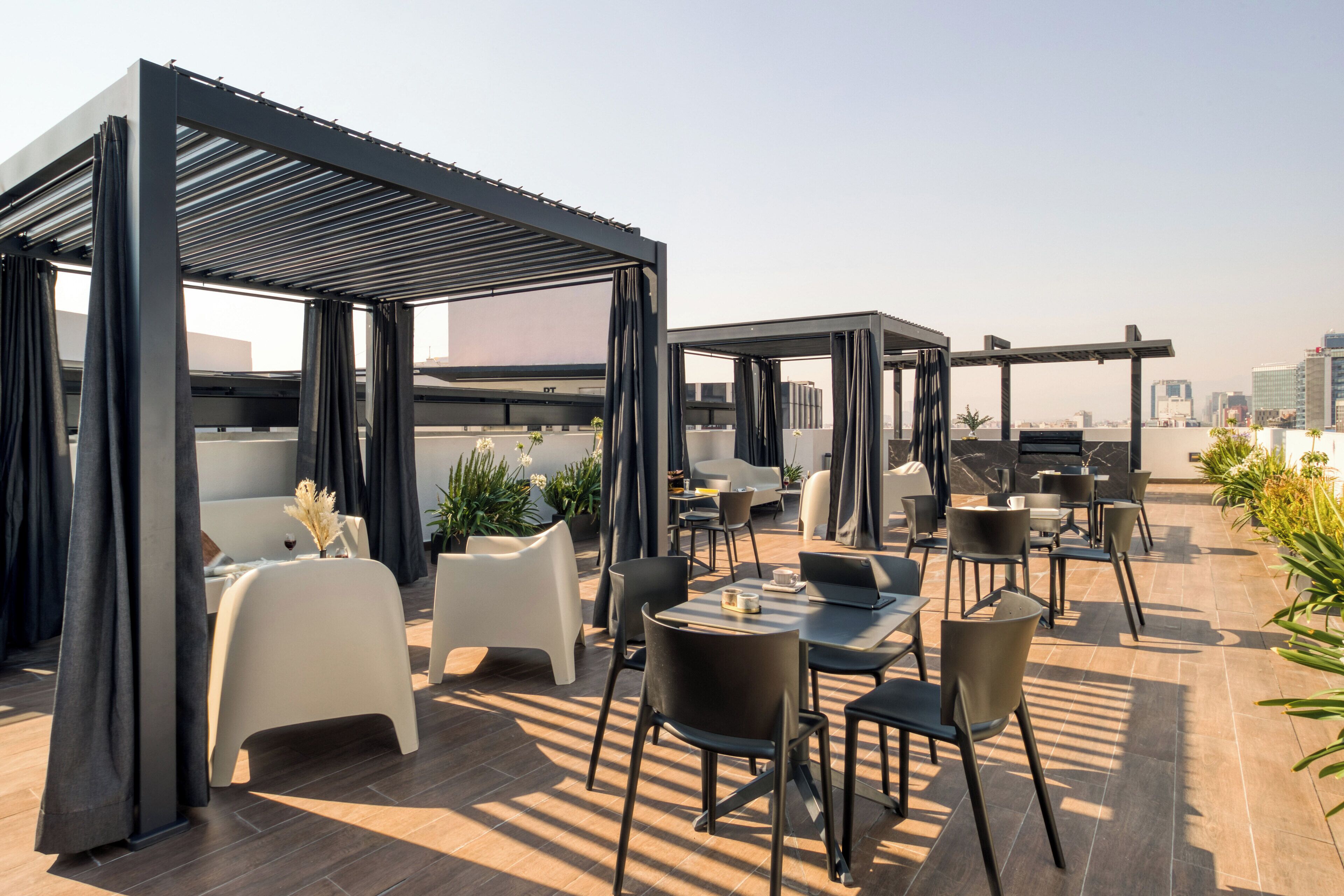 An outdoor rooftop lounge with modern seating and a city view.