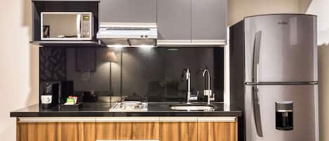 A modern kitchen with a built-in microwave, stainless steel refrigerator, and wooden cabinets.