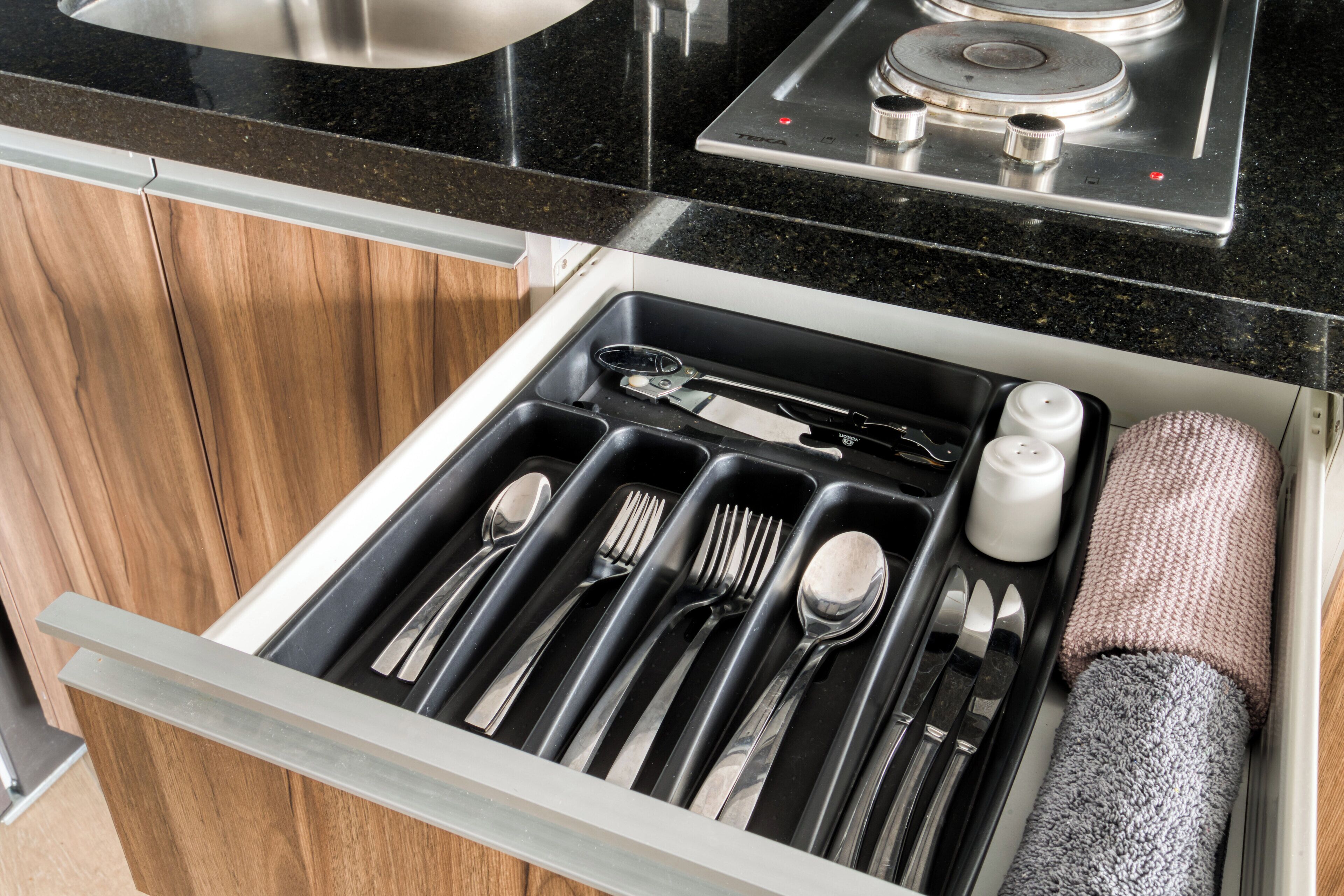 A kitchen drawer with utensils and a towel.