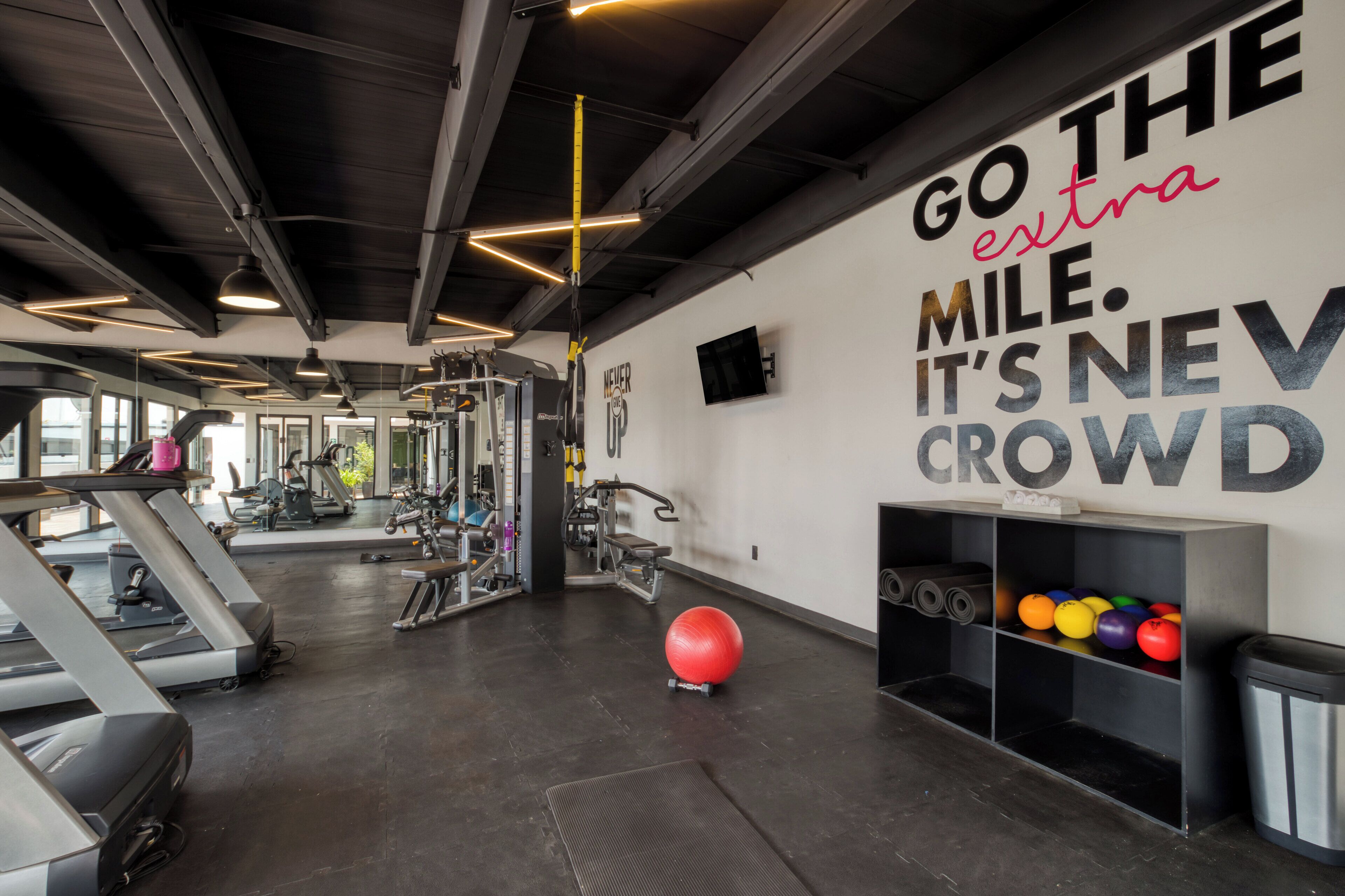 A gym with treadmills, exercise equipment, and a motivational quote on the wall.