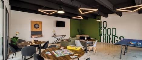 A modern indoor space with a dartboard, ping pong table, and a motivational wall saying "DO GOOD THINGS".