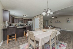 A modern kitchen with dark wooden cabinets, a central island, and a dining area with a table and chairs.