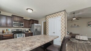 A kitchen with dark wooden cabinets, a granite countertop, and a stainless steel refrigerator.