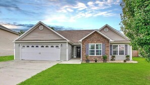 A single-story house with a garage, a stone accent wall, and a well-maintained lawn.