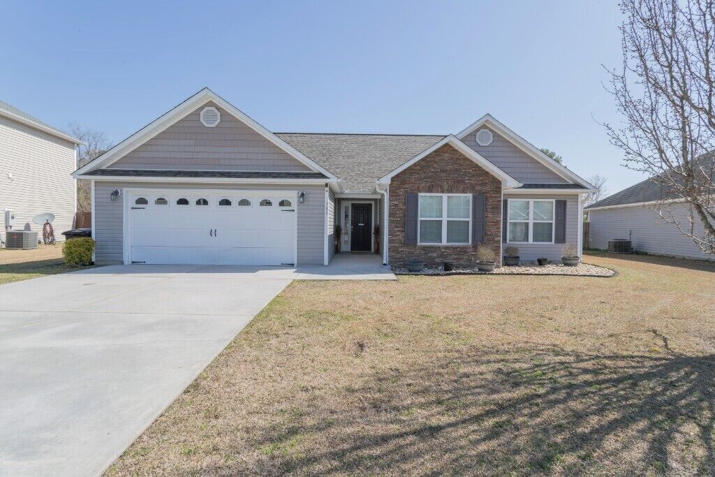 A single-story house with a garage, a small front porch, and a brick section.
