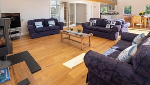 A modern living room with two dark blue sofas, a wooden coffee table, and a flat-screen TV. - Moult Hill Barn (Salcombe)