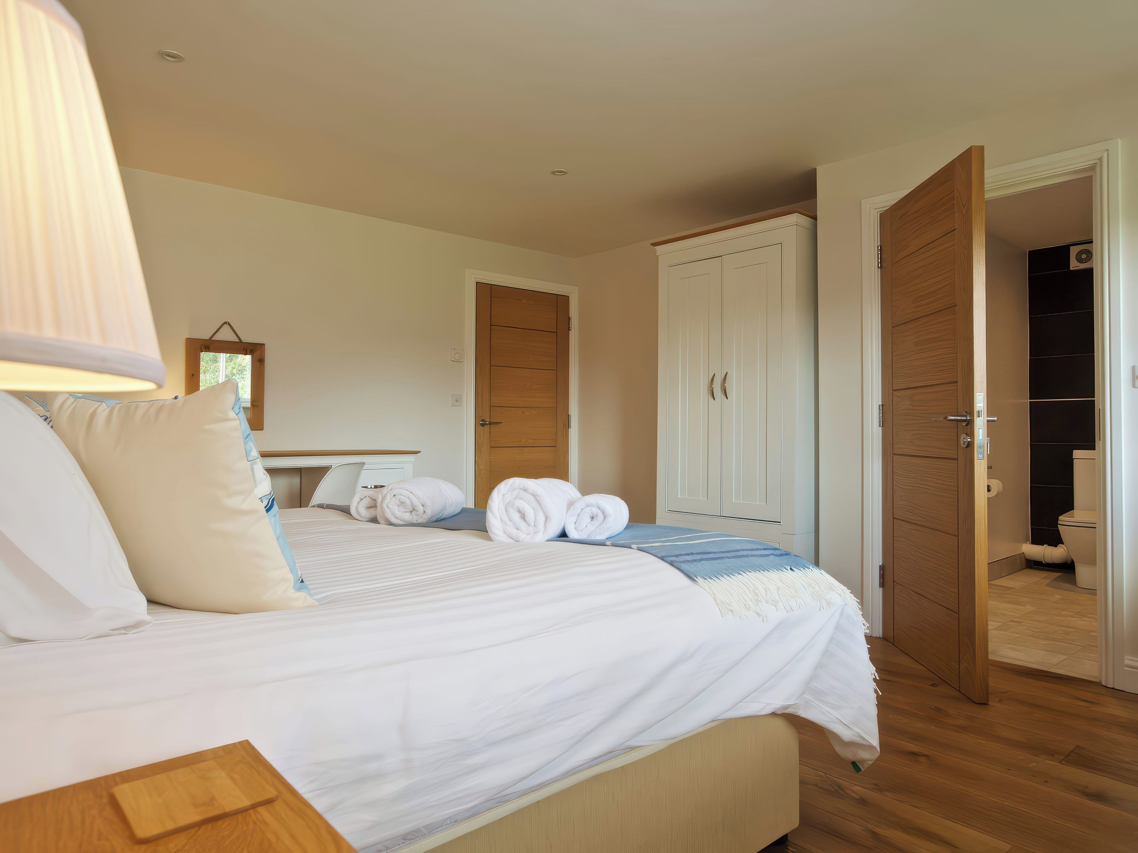 A hotel room with a bed, a desk, a wardrobe, and a bathroom.