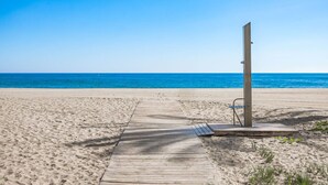 A wooden boardwalk leading to a beach with a metal structure on the right. - Front Line Playa Rocio P. Banus (Marbella)