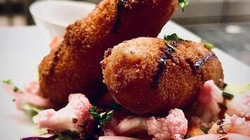 Een bord met gepaneerde en gefrituurde snacks, mogelijk kroketten, geserveerd met een salade.