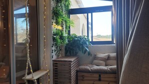A cozy corner with a cushioned bench, a wooden crate, and a hanging plant.