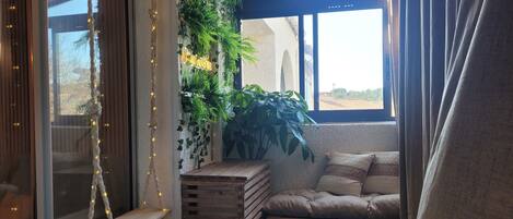 A cozy corner with a cushioned bench, a wooden crate, and a hanging plant.