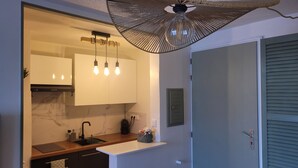 A modern kitchen with a marble countertop, a built-in oven, and a hanging light fixture.