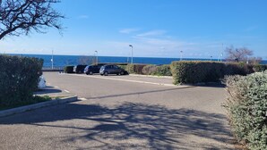 A parking area with cars and a view of the sea.