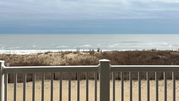 A beach view from a covered area with a white railing. - Charming 2-bedroom condo with WiFi, AC in amazing Ocean City (Ocean City)