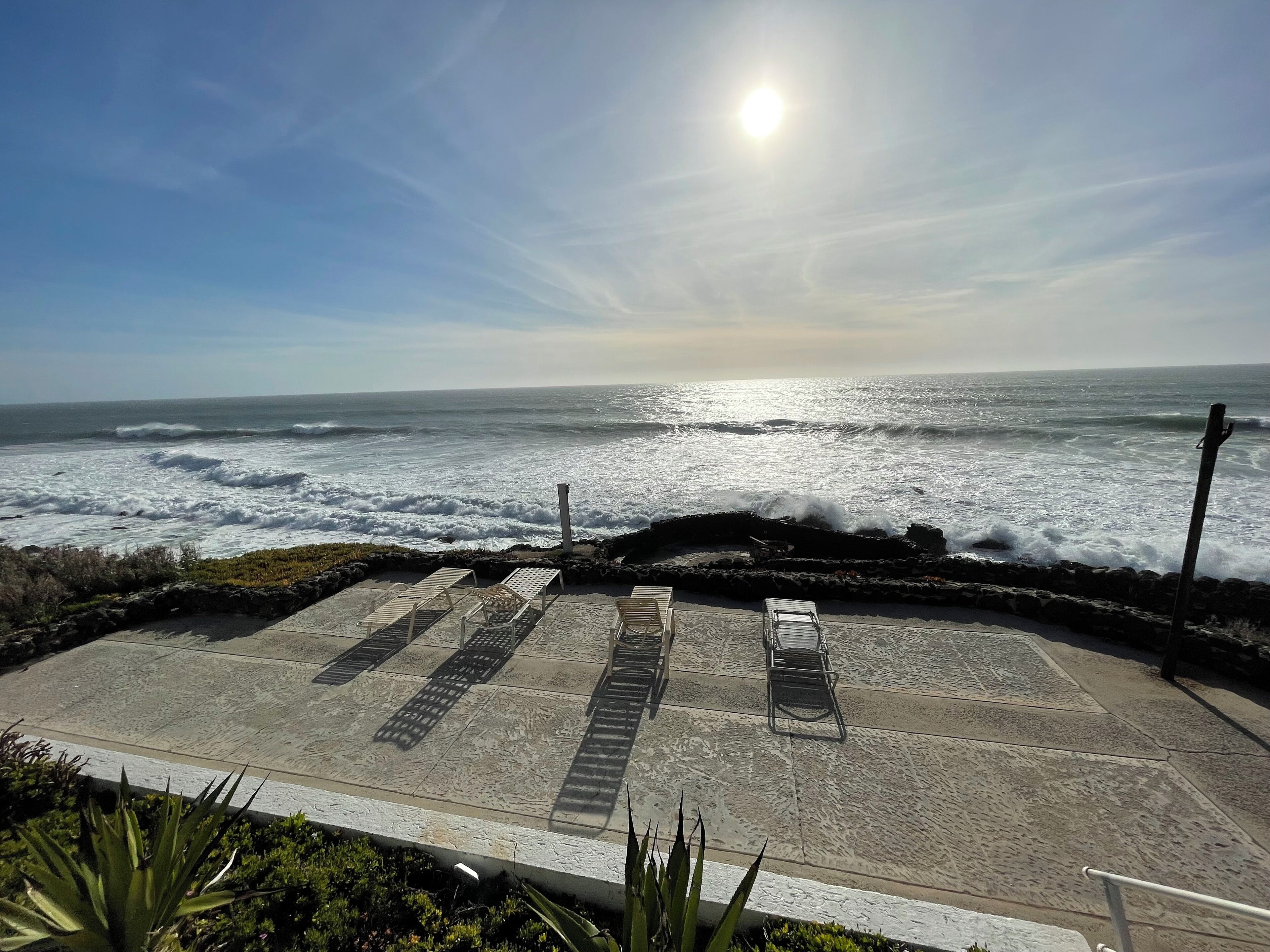 A beachside parking area with a view of the ocean and a clear sky.
