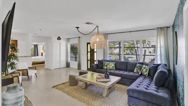 A modern living room with a sofa, coffee table, and a hanging light fixture. - Welcome To The Leaf House (Delray Beach)