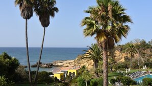 A coastal resort with palm trees, a pool, and a view of the ocean. - NEW apt. 1 min. walk from beach, sea view, large terrace, two pools (Albufeira)