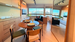Cozinha moderna com área de refeições, grandes janelas e vista para a cidade.