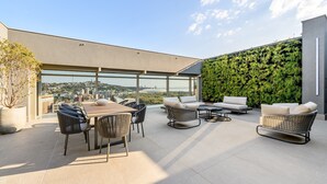 Terraço no telhado com área de jantar, assentos e parede verde.