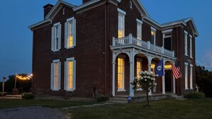 A large brick building with a balcony and a flag. - Historic Home & Farm in Bourbon Country  (Warsaw)