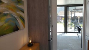 A modern kitchen with a wooden cabinet, a glass door leading to a patio, and a painting on the wall.