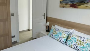 A hotel room with a bed, a nightstand, a lamp, and a painting on the wall.