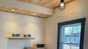 A kitchen with a wooden countertop, a sink, a stove, and a window with a view of houses outside.