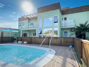 Un bâtiment à deux étages doté d’une piscine, d’une terrasse en bois et d’un espace clôturé.