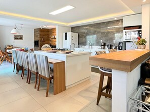 A modern kitchen with a central island, white cabinetry, and a dining area with striped chairs.