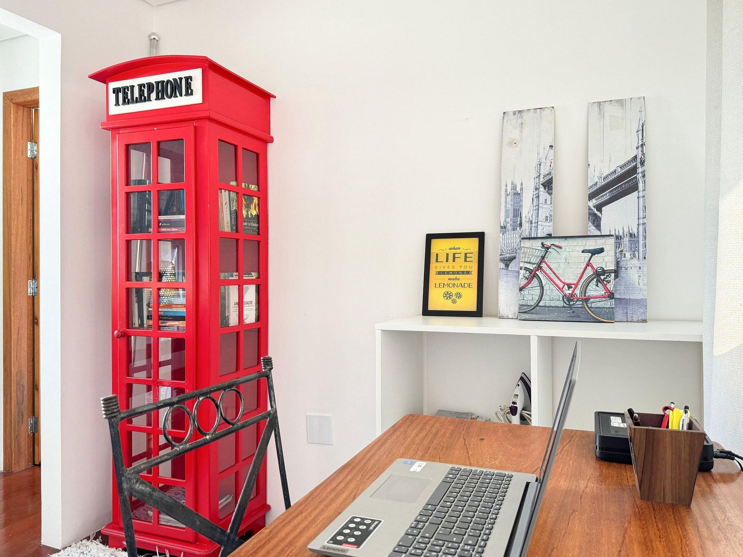 Ein Zimmer mit einer roten Telefonzelle, einem gerahmten Zitat an der Wand und einer Fahrradgrafik.