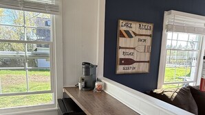 A kitchen with a wooden countertop, two stools, a coffee maker, and a wall decoration. - Studio cottage in Bar Harbor - Cozy 1930's Fireplace, Sleeps 3. (Bar Harbor)