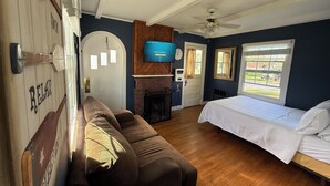 A bedroom with a bed, a sofa, a television, and a fireplace. - Studio cottage in Bar Harbor - Cozy 1930's Fireplace, Sleeps 3. (Bar Harbor)