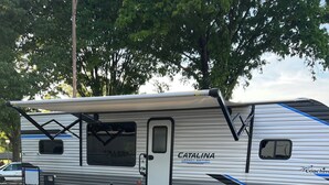 A Catalina Legacy Edition RV with a sliding door, a small window, and a side ramp. - Cozy campground with WiFi and AC.  Walk to the Charlotte motor speedway. (Concord)