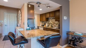 A modern kitchen with granite countertops, dark wooden cabinets, and a built-in wine rack. - Forest Beach Villas - 5 Min. Walk to Coligny Beach (Hilton Head Island)