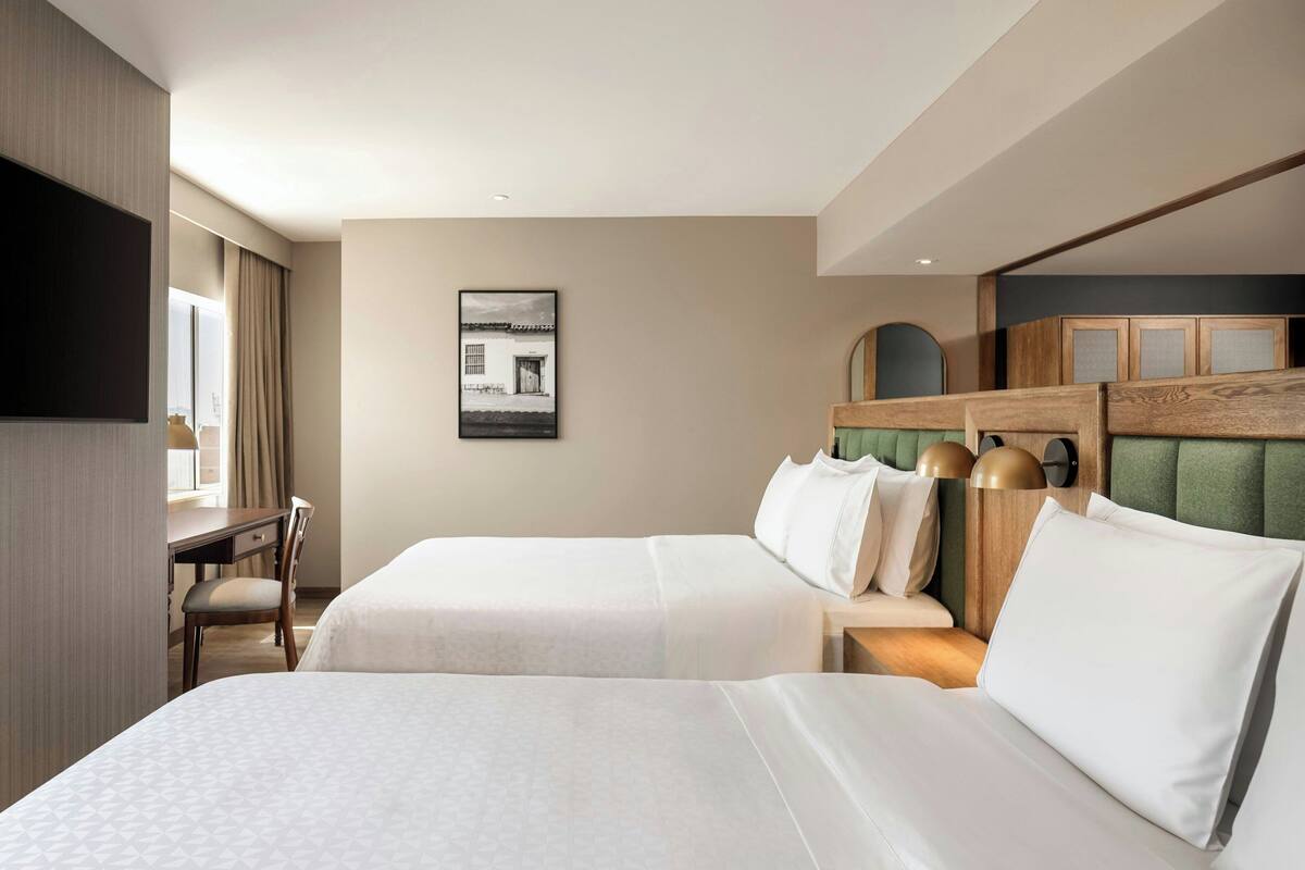 Une chambre d’hôtel avec deux lits, un bureau et une télévision.