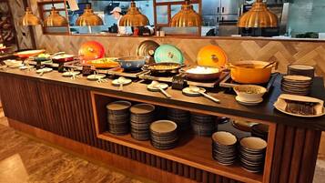 Mesa de buffet com diversos pratos e utensílios.