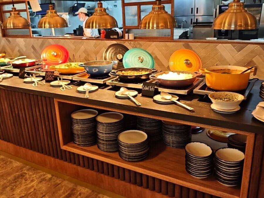 Mesa de buffet com diversos pratos e utensílios.