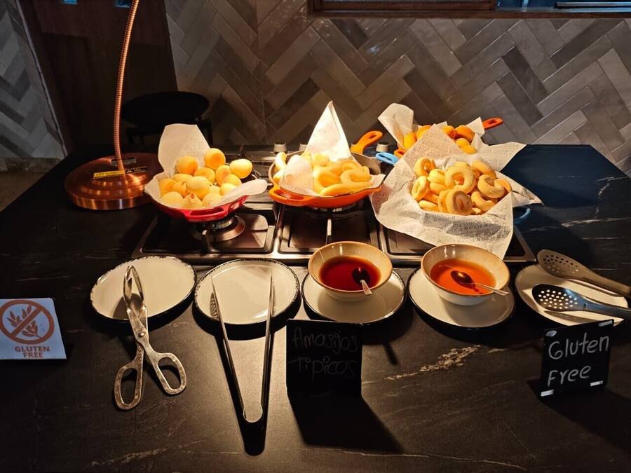 A buffet table with various food items, including bread rolls and dips, and signs indicating gluten-free options.