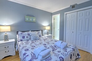 Ein Schlafzimmer mit einem Bett, zwei Nachttischen, einem Schrank und einer Tür.