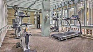 Un gimnasio con cintas de correr, bicicletas estáticas y elípticas.