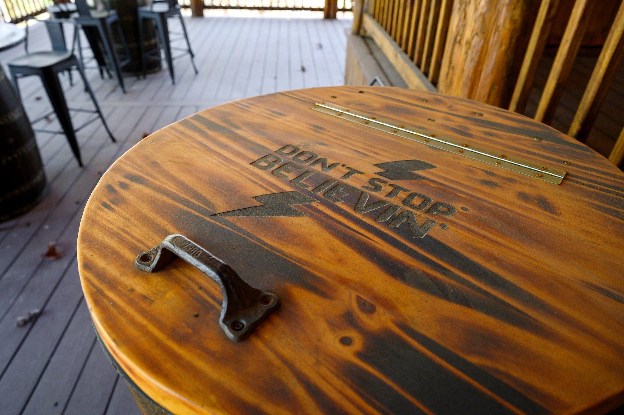 A wooden table with a metal handle and the words "DON'T STOP BELIEVIN" engraved on it.