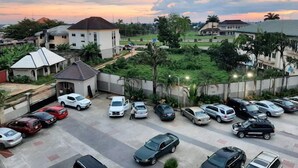 A parking lot with multiple cars and a residential area with houses and greenery. - Watbridge Hotel and Suites (Uyo)