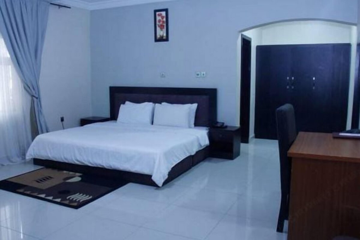 A bedroom with a bed, bedside tables, a desk, and a wardrobe.