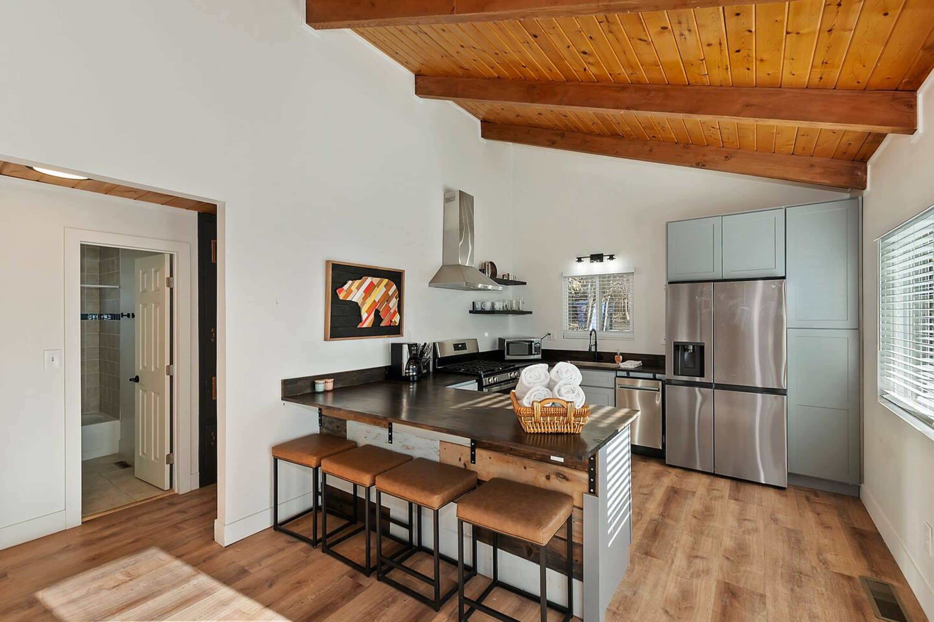 A modern kitchen with a central island, stainless steel appliances, and wooden flooring.