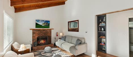 Una sala de estar con chimenea, un sofá, una mesita de centro y una alfombra estampada.