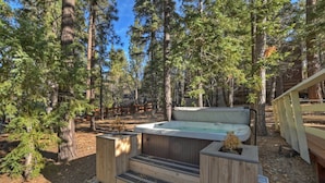 A hot tub in a forested area with wooden steps leading up to it. - Peaceful Sunshine Chalet with Hot Tub (Big Bear Lake)