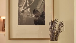 A framed photograph on a wall, a vase with dried flowers on a table, and a rectangular object on the table. - Brand new community- Prime Highland Park! Unit 2 (Los Angeles)