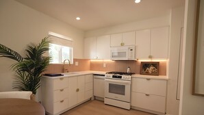 A modern kitchen with white cabinets, a built-in microwave, a stove, and a sink. - Brand new community- Prime Highland Park! Unit 2 (Los Angeles)