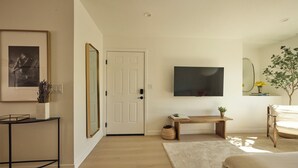 A modern bedroom with a bed, a bedside table, a mirror, and a TV on the wall. - Brand new community- Prime Highland Park! Unit 2 (Los Angeles)